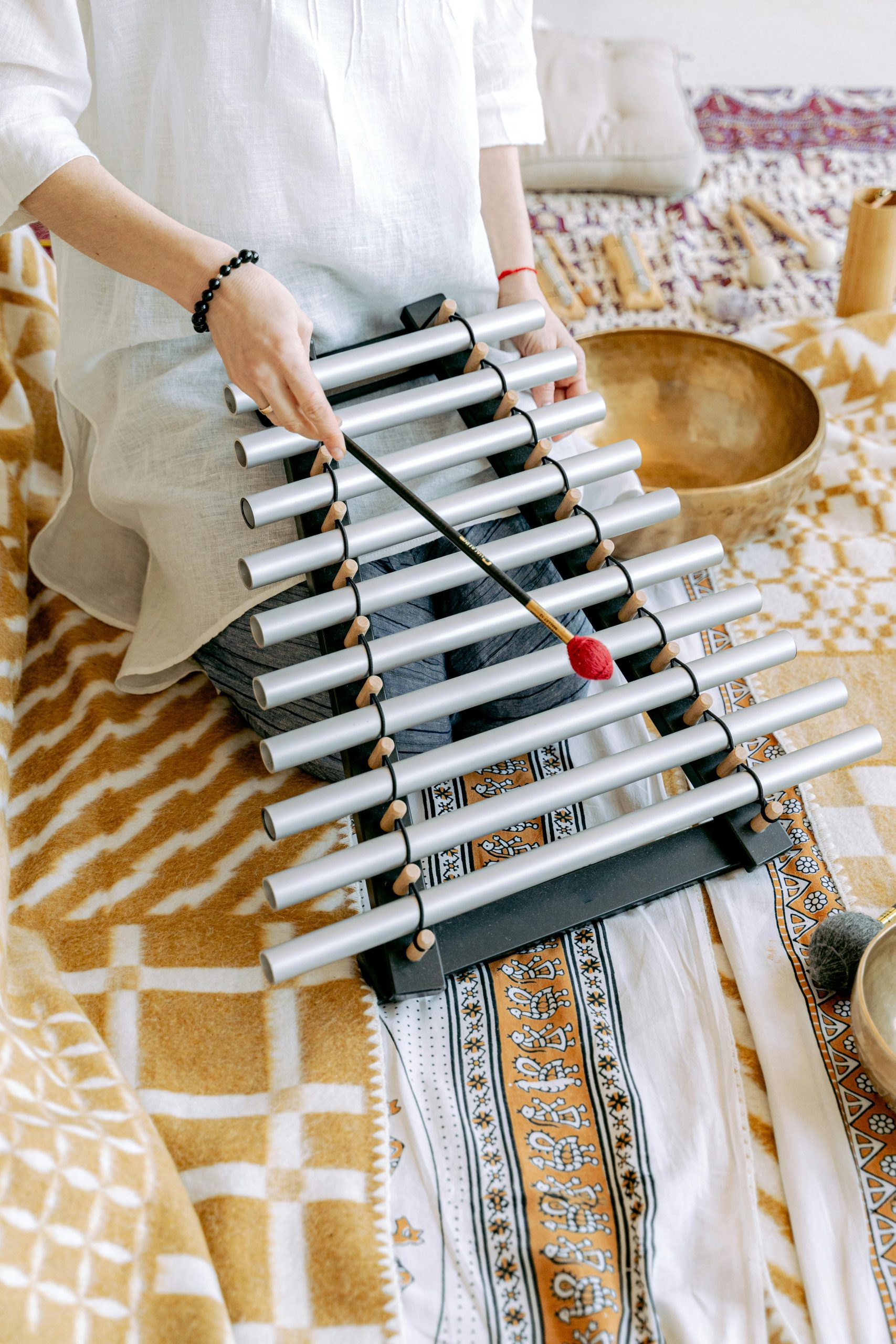 A soothing sound therapy session featuring tubular bells and a mallet on a patterned blanket.